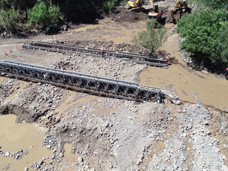 Vista aérea de puentes provisorios sobre un cauce afectado por un aluvión