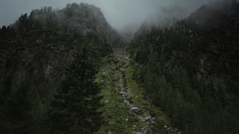 Quebrada de ladera empinada con bloques de roca bajo la neblina